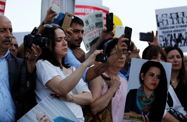 Journalists and press freedom activists take pictures and videos during a demonstration in solidarity with the members of the opposition newspaper Cumhuriyet who were accused of supporting a terrorist group outside a courthouse, in Istanbul